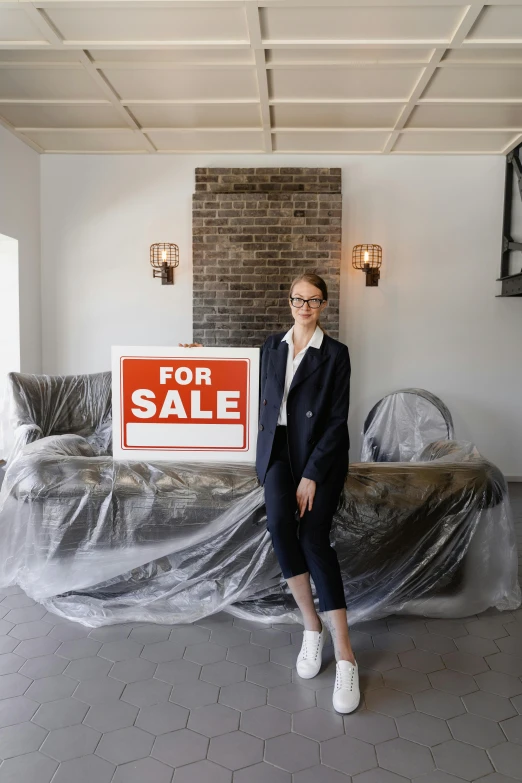 a woman standing in a living room holding a for sale sign, by Carey Morris, trending on unsplash, modernism, wearing a suit and glasses, construction, very large, in a old house. hyper realistic