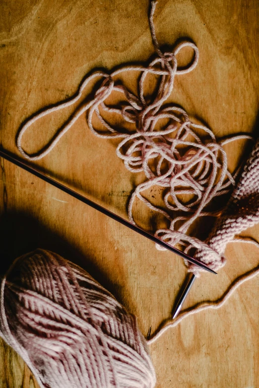 a ball of yarn sitting on top of a wooden table, brown and pink color scheme, ripped clothes holding whip, promo image, uncrop