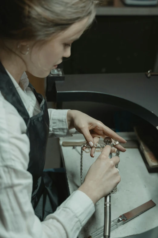 a woman is working on a piece of jewelry, an engraving, inspired by Anna Füssli, trending on unsplash, 2 0 2 1 cinematic 4 k framegrab, ignant, 8k 28mm cinematic photo, mechanic