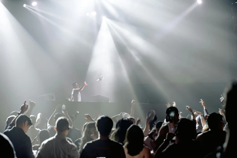 a group of people that are standing in front of a stage, pexels contest winner, happening, dj at a party, very bright white light, dramatic lighting from above, fan favorite