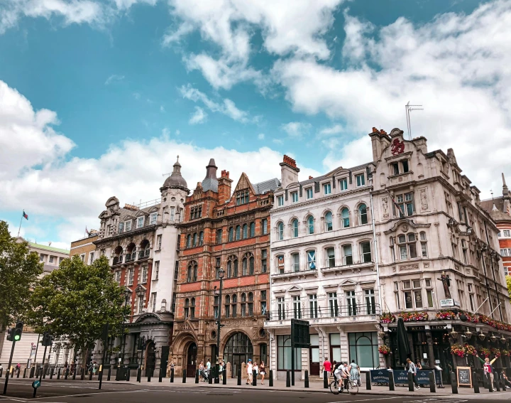 a group of buildings sitting on the side of a road, inspired by Edward Kemble, pexels contest winner, art nouveau, square, victorian london, bright sky, audrey plaza