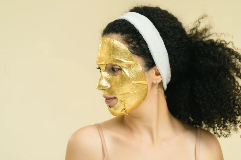 a woman with a gold mask on her face, trending on pexels, manuka, clear [bronze] face, cardboard, middle eastern skin