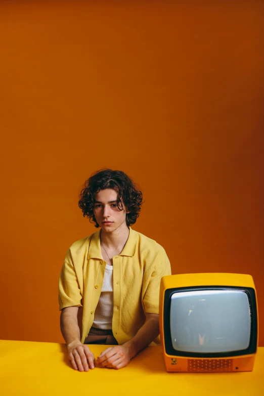 a man sitting in front of a yellow television, an album cover, pexels, timothee chalamet, ariel perez, shot in the photo studio, rebecca sugar