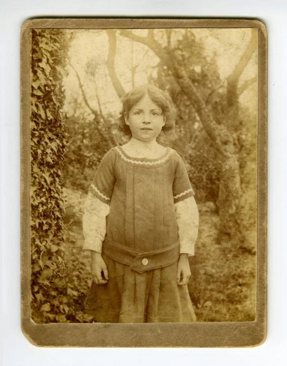 an old photo of a little girl in a dress, a black and white photo, with blunt brown border, set photograph