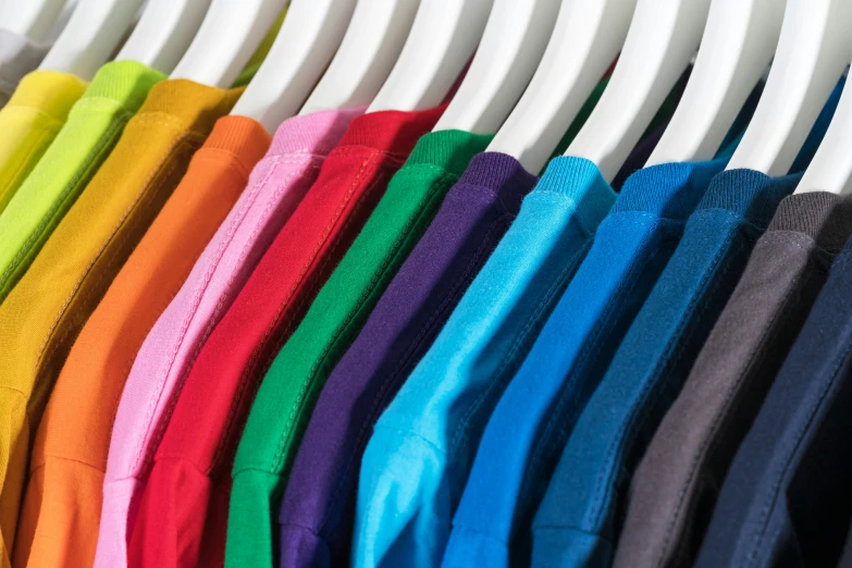 a row of colorful shirts hanging on a rack, pexels, color field, wearing a t-shirt, full colour spectrum, upclose, solid colours