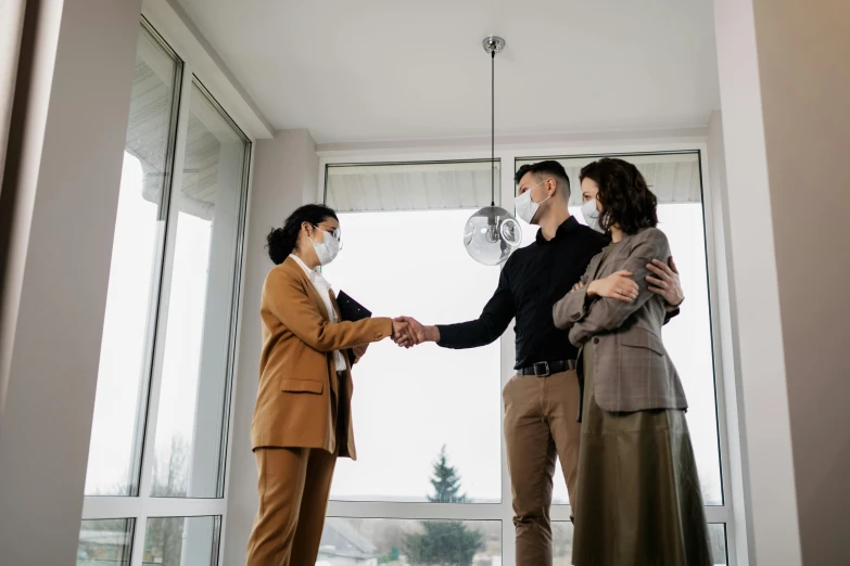 a group of people shaking hands in front of a window, mask off, location in a apartment, professional modeling, well - appointed space