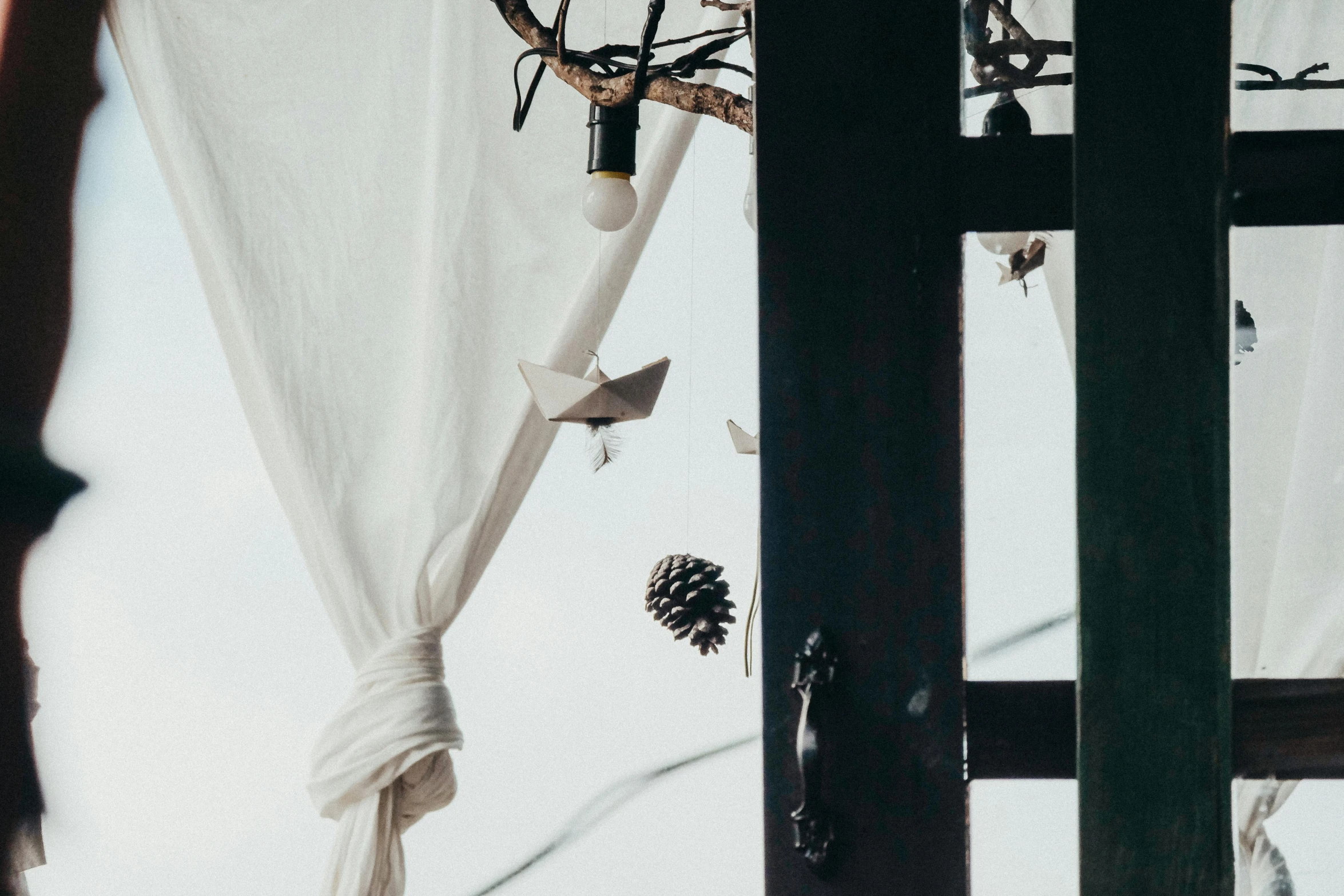 a white curtain hanging from the side of a window, inspired by Cerith Wyn Evans, trending on unsplash, festive atmosphere, lantern light besides, pine treehouse, mixed materials