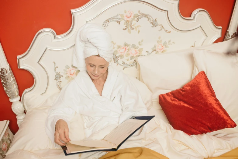 a woman in a bathrobe reading a book on a bed, an album cover, inspired by Thomas Stothard, pexels, elderly woman, wearing a turban, white-haired, profile image