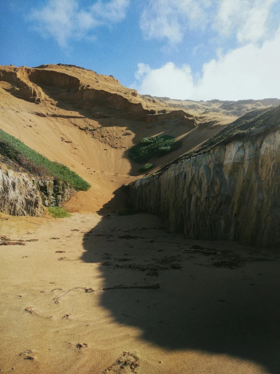 a man riding a surfboard on top of a sandy beach, a matte painting, unsplash, les nabis, landslide road, erosion, icelandic valley, sand - colored walls