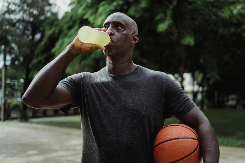 a man drinking from a bottle while holding a basketball, pexels contest winner, dave chappelle, lemonade, athletic muscle tone, 🍸🍋