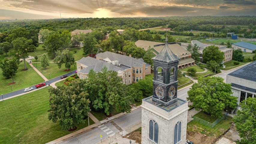 a large clock tower sitting in the middle of a lush green field, academic art, drone photograph, bentonville arkansas, listing image, sunset view