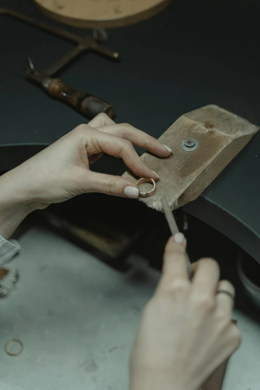 a person cutting a piece of wood with a knife, silver jewellery, ivory and copper, teaser, middle shot