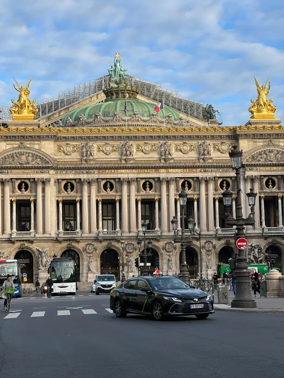 a group of cars driving down a street next to a tall building, art nouveau, splendid haussmann architecture, profile image, photo of a big theaterstage, promo image