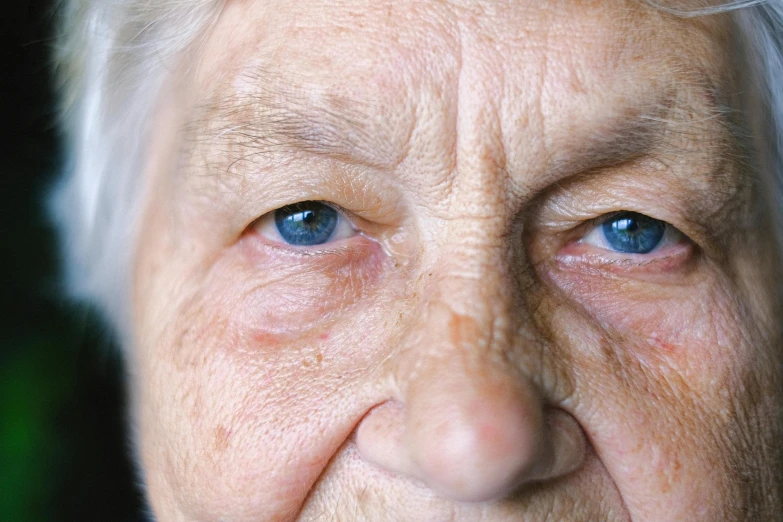 an older woman with white hair and blue eyes, a stipple, unsplash, noticeable tear on the cheek, full body close-up shot, wrinkly, close - up photo