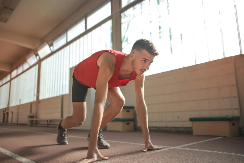 a man is preparing to run on a track, a portrait, pexels contest winner, profile image, thumbnail, indoor picture, wearing red shorts