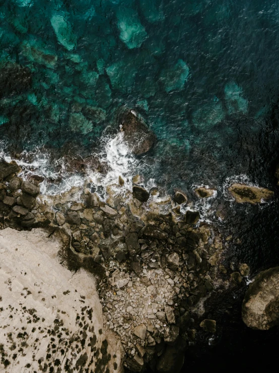 an aerial view of a large body of water, a screenshot, pexels contest winner, wet rocks, high light on the left, bold composition