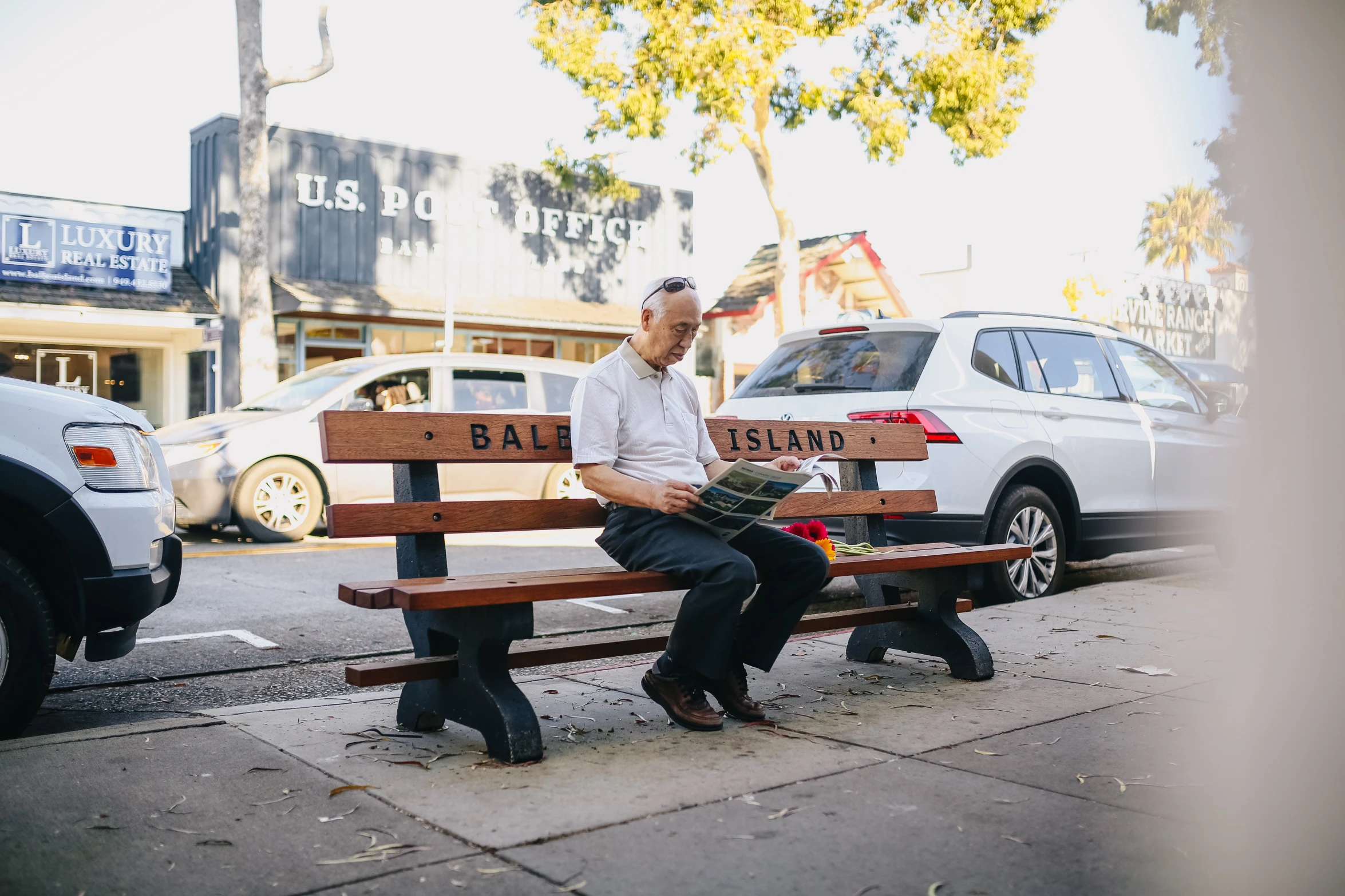 a man sitting on top of a wooden bench, inspired by Robert Ballagh, unsplash, realism, the city of santa barbara, he is holding a large book, colonel sanders, north melbourne street