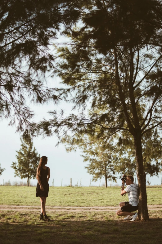 a couple of people that are standing in the grass, by Lucia Peka, pexels contest winner, happening, sitting under a tree, man proposing his girlfriend, brazil, panoramic view of girl