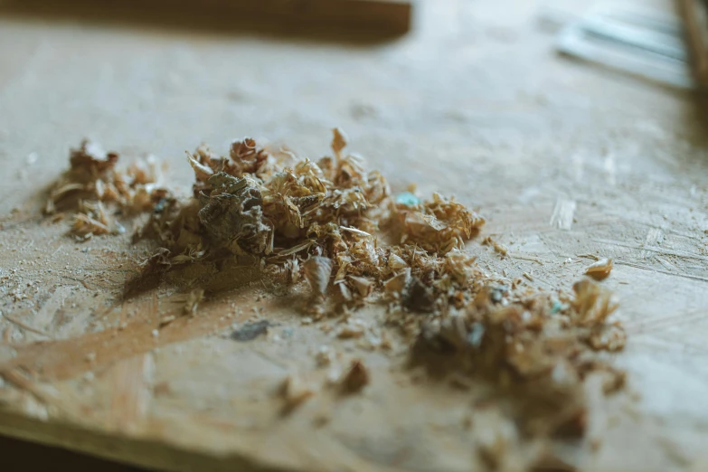 a knife sitting on top of a wooden cutting board, a macro photograph, by Jessie Algie, unsplash, process art, debris on the floor, ignant, woodlathe, smoking a bowl of hash together