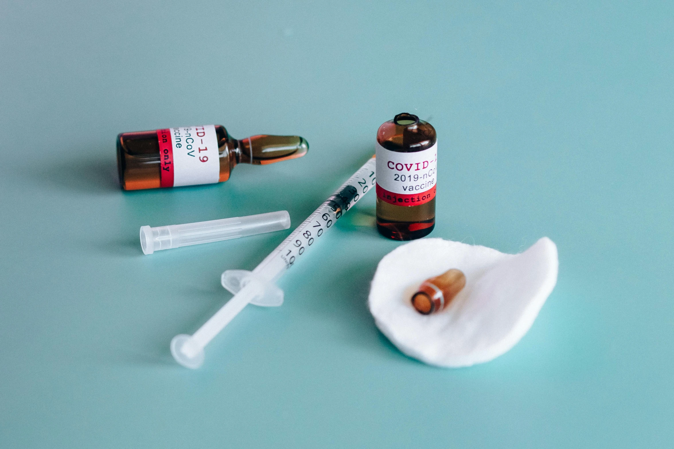 a syll, a bottle of pills, and a syll on a blue surface, by Julia Pishtar, pexels, surgical iv drip, poster of corona virus, red brown and white color scheme, syringe