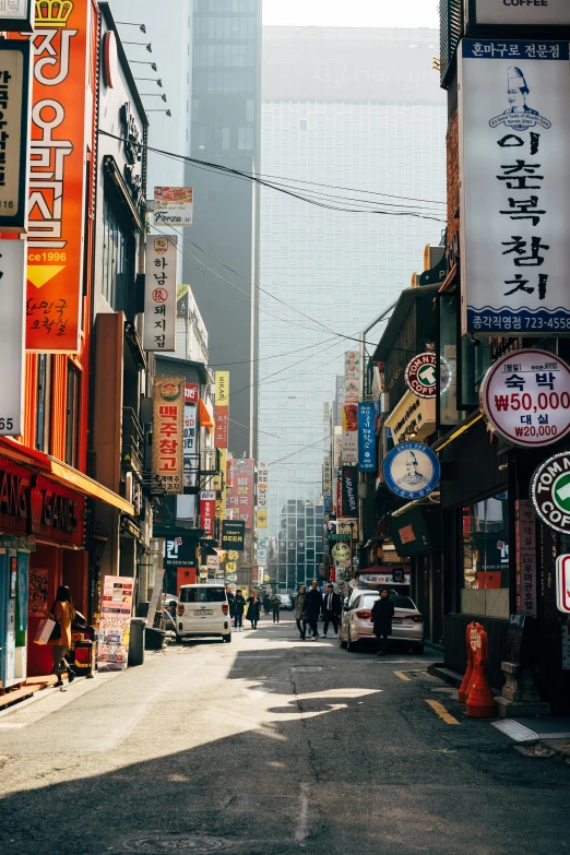 a city street filled with lots of tall buildings, a picture, inspired by jeonseok lee, trending on unsplash, colorful signs, historical photo, square, south east asian with long