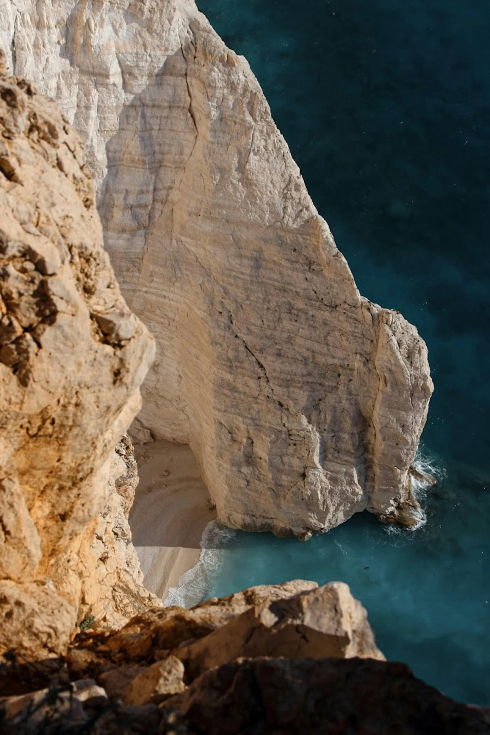 a man standing on top of a cliff next to a body of water, inspired by Nassos Daphnis, pexels contest winner, zoomed in, chalk cliffs above, evening lighting, red sea