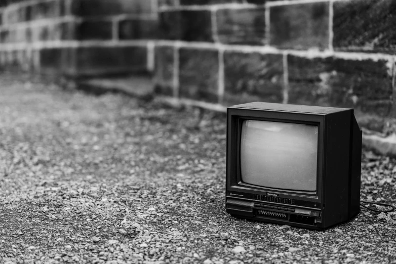 an old television sitting in front of a brick wall, a black and white photo, by Matija Jama, pixabay, video art, instagram post, 1 9 8 0 s tech, run down, tv show still