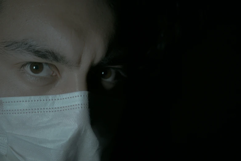 a close up of a person wearing a face mask, an album cover, dark scene, doctor, 8 k film still, frightened look
