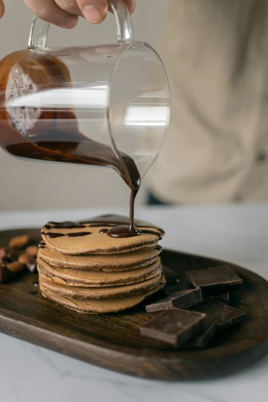 a person pouring chocolate onto a stack of cookies, by Daniel Seghers, pexels contest winner, renaissance, living food adorable pancake, on a wooden tray, larapi, gif