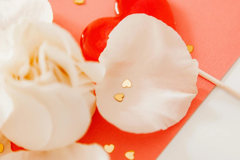 a close up of a flower on a stick, rose gold heart, gold earring, confetti, thumbnail