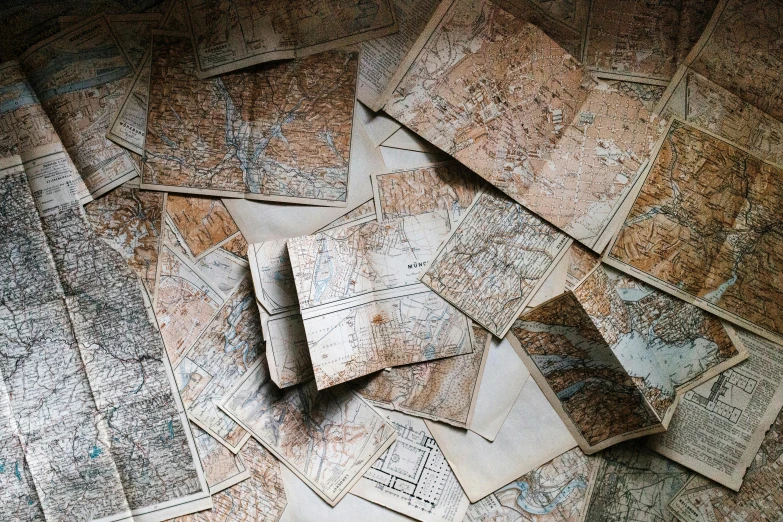 a pile of old maps sitting on top of a table, by Jessie Algie, pexels, maze of streets, instagram post, brown, thumbnail