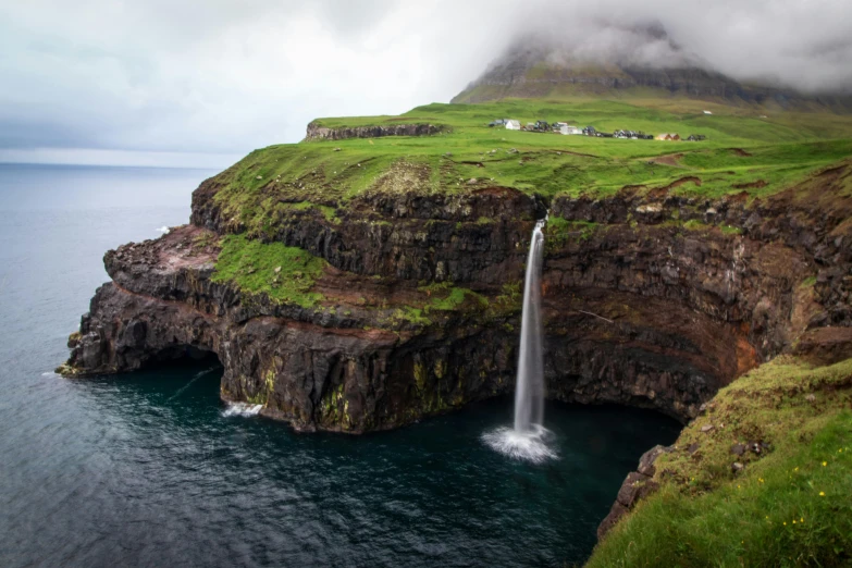 a waterfall in the middle of a large body of water, by Daren Bader, pexels contest winner, faroe, farming, mediterranean island scenery, conde nast traveler photo