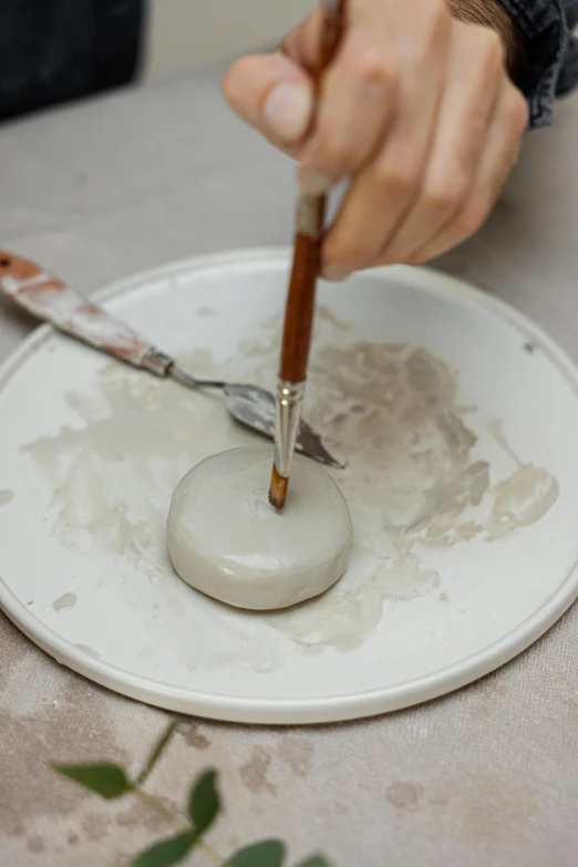 a close up of a person using a paintbrush on a plate, a marble sculpture, inspired by Hendrik Gerritsz Pot, smooth round rocks, white clay, anya forger, ready to model