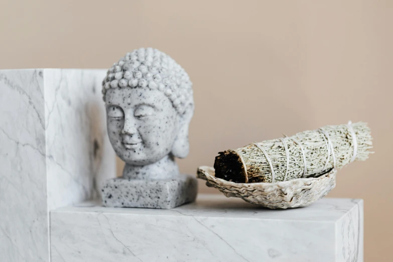 a buddha statue sitting on top of a marble block, a marble sculpture, inspired by Ma Quan, trending on unsplash, with seaweed, wearing silver silk robe, small chin, detailed product photo