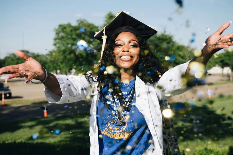 a woman in a graduation gown throwing confetti, a portrait, pexels, academic art, white + blue + gold + black, sza, african american woman, a still of a happy