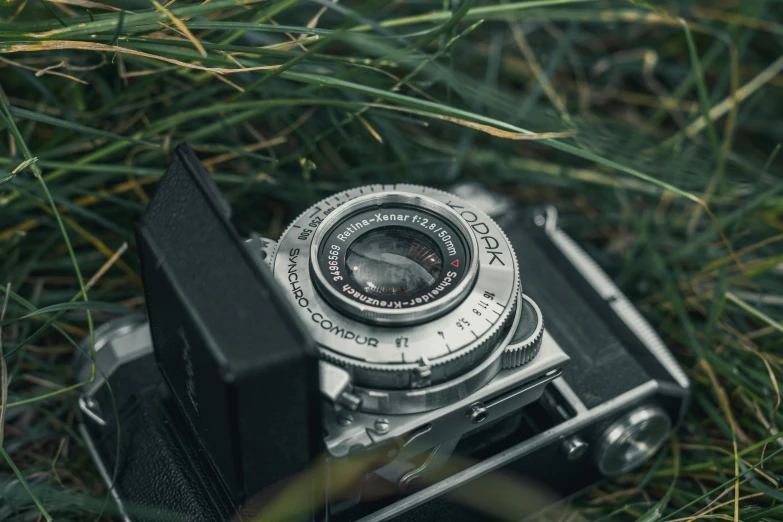 an old camera is laying in the grass, by Adam Marczyński, unsplash contest winner, photorealism, medium format, monocular, 1940s photography, medium format color photography