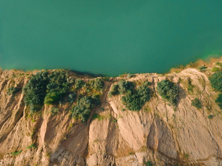 an aerial view of a large body of water, trending on unsplash, rock quarry location, a green, thumbnail, sloped site