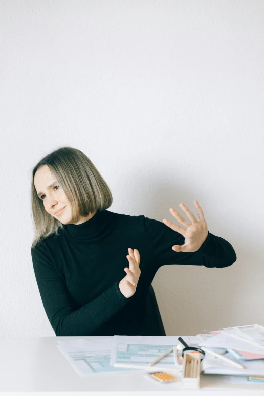 a woman sitting at a table with her hands in the air, an album cover, inspired by Anna Füssli, unsplash, altermodern, wearing turtleneck, dabbing, gif, low quality photo