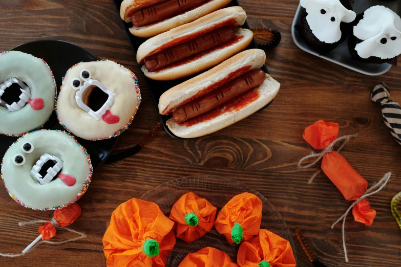 a table topped with hot dogs covered in frosting, a still life, by Julia Pishtar, pexels, halloween decorations, background image, halo halo halo halo 8k, anonymous as a sausage