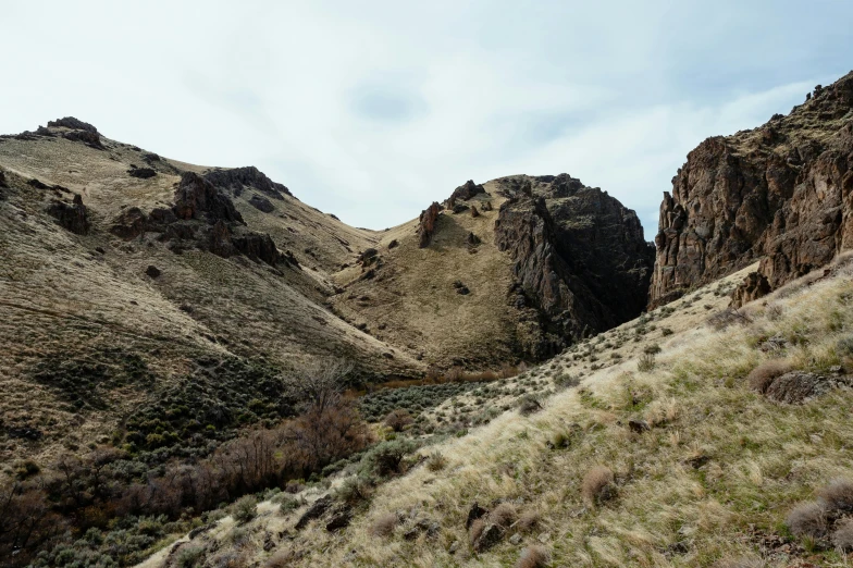 a man riding a horse on top of a lush green hillside, an album cover, by Jessie Algie, unsplash, les nabis, extremely detailed rocky crag, oregon, dry river bed, photo from the dig site