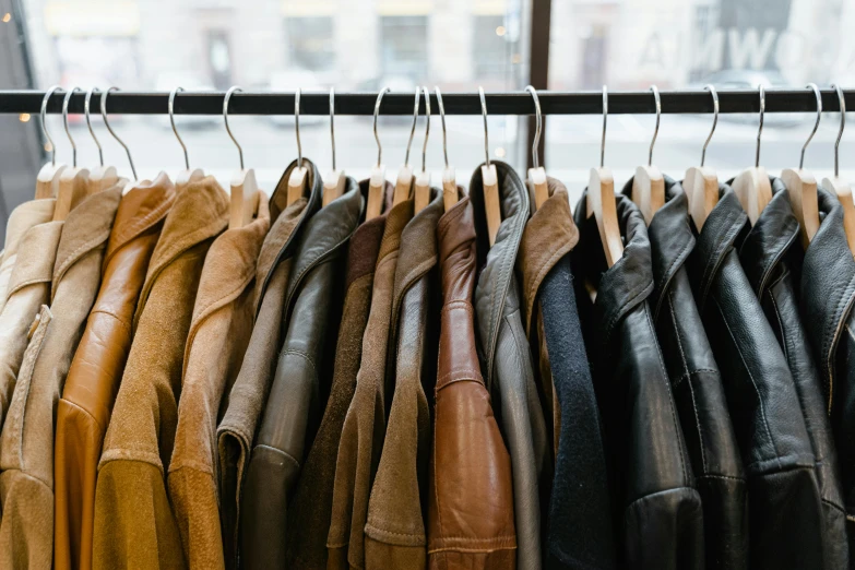 a rack of leather jackets in front of a window, trending on unsplash, renaissance, muted brown yellow and blacks, inspect in inventory image, thumbnail, 70s colors