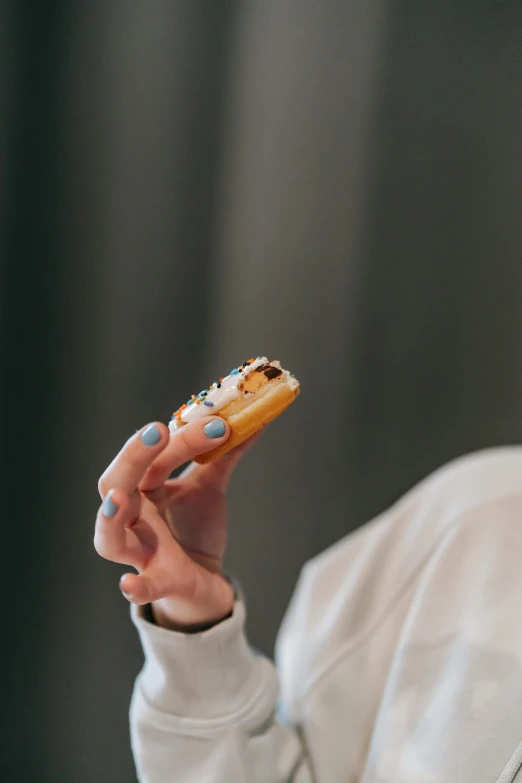 a woman holding a donut in one hand and a donut in the other, by Niko Henrichon, unsplash, cigarette, profile image, show, small