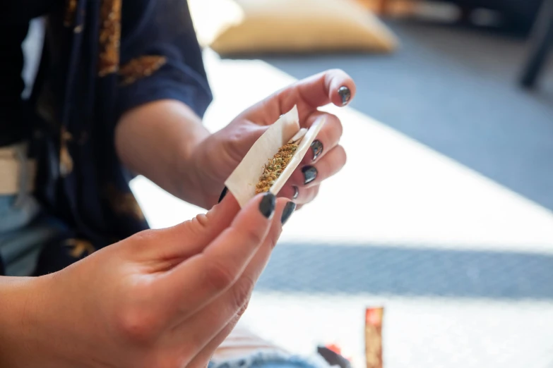 a close up of a person holding a piece of food, smoking a joint, white white and gold kintsugi, high samples, person in foreground