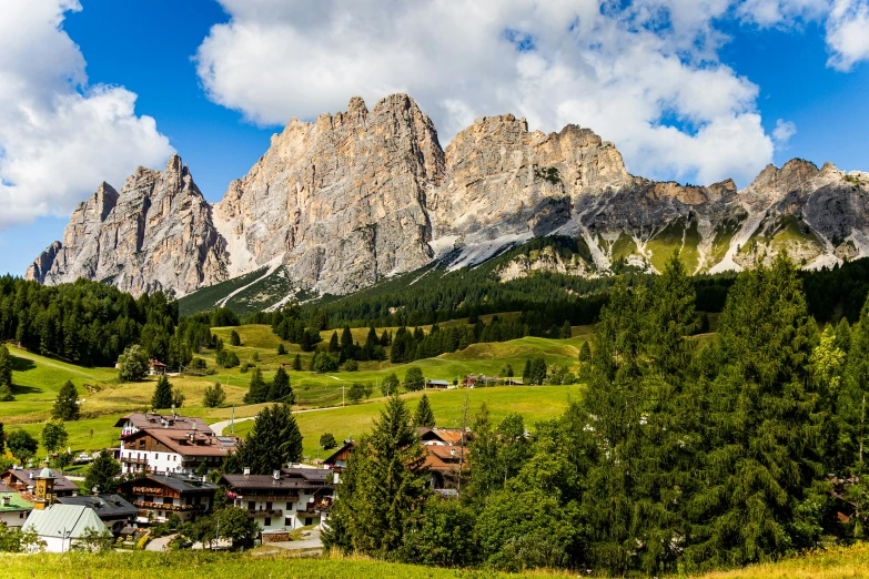 a small village with mountains in the background, by Carlo Martini, pexels contest winner, dolomites, lush surroundings, panoramic, slide show