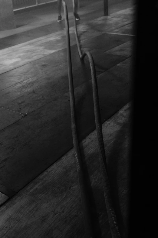 a man riding a skateboard up the side of a ramp, a black and white photo, inspired by Roy DeCarava, unsplash, lyrical abstraction, cables on floor, abstract detail, in a dark warehouse, ((still life))