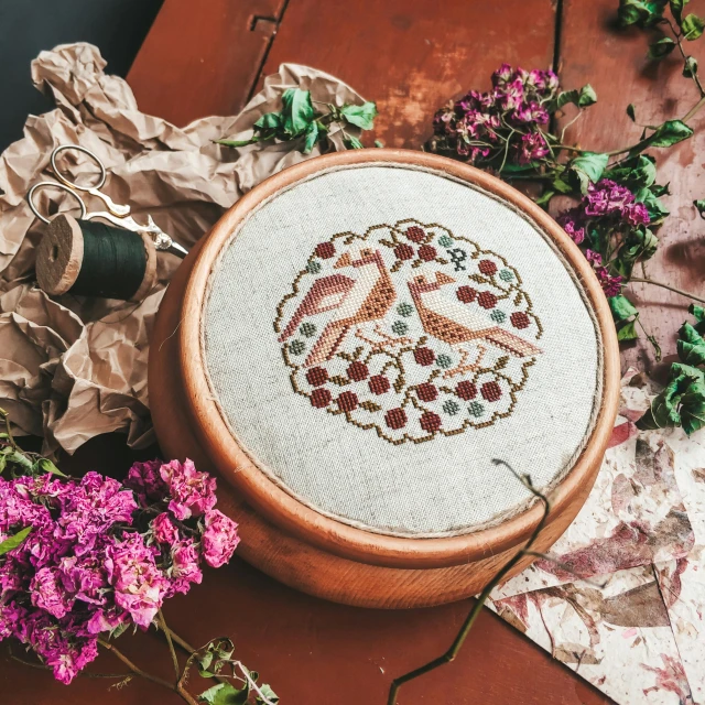 a wooden bowl sitting on top of a table next to a bunch of flowers, a cross stitch, by Emma Andijewska, pexels contest winner, folk art, birds on cherry tree, perfectly detailed linework, in a wooden box. top down photo, round format