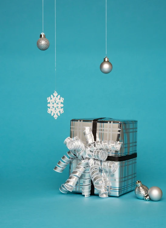 a silver gift box sitting on top of a blue surface, by Alice Mason, shutterstock contest winner, ornaments, gif, hanging, mix