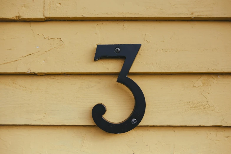 a house number on the side of a house, inspired by Clarice Beckett, unsplash, yellow and black, threes, modeled, metallic