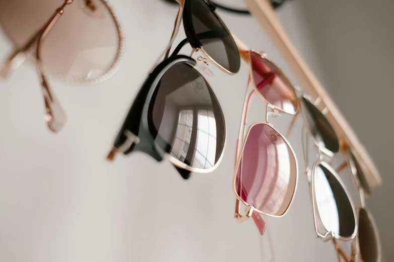 a rack with several pairs of sunglasses hanging from it, trending on pexels, square rimmed glasses, soft details, over-shoulder shot, tans