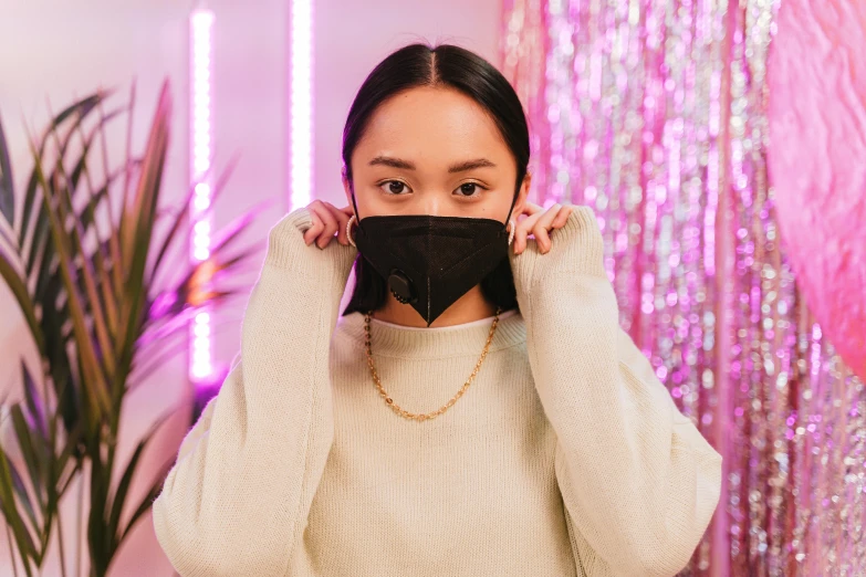 a woman covering her face with a black mask, trending on pexels, wearing gold chain, kawaii vibe, fancy background, pointed chin